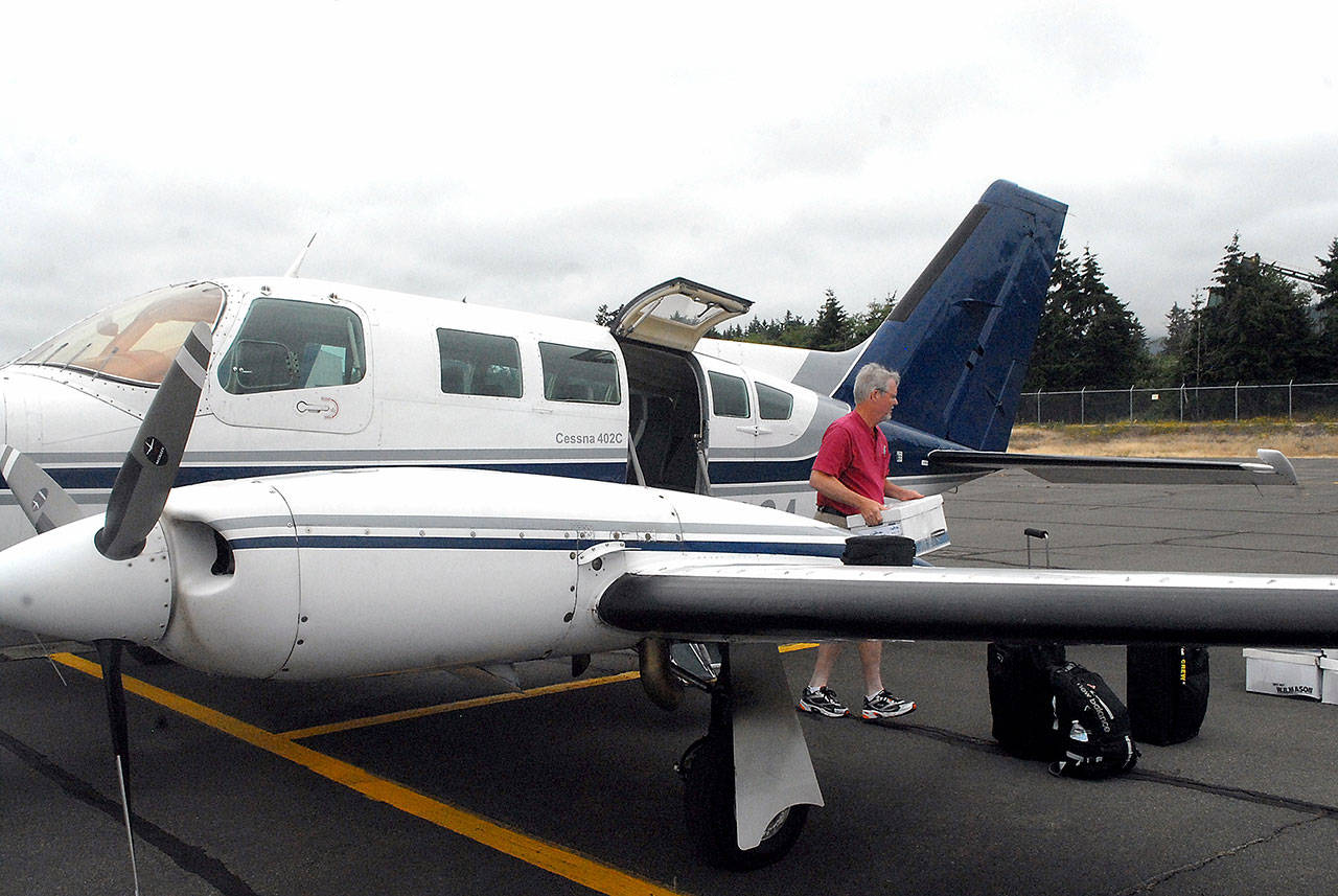 Aspiring Dash pilot Josh Crabtree of Port Angeles unloads boxes of maintenance records from a Dash Air Shuttle Cessna 402C on Wednesday at William R. Fairchild International Airport in Port Angeles. (Keith Thorpe/Peninsula Daily News)