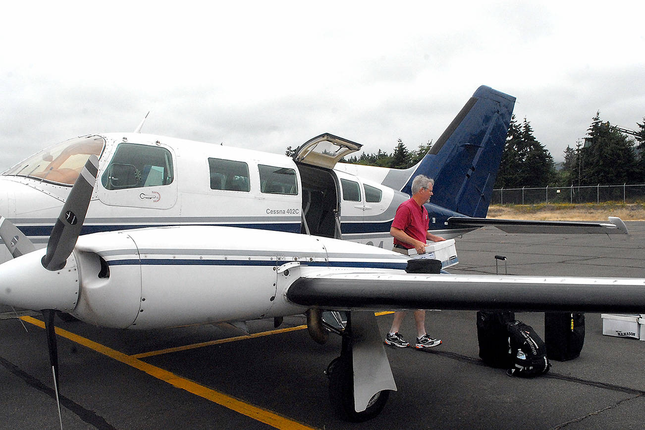 Aspiring Dash pilot Josh Crabtree of Port Angeles unloads boxes of maintenance records from a Dash Air Shuttle Cessna 402C on Wednesday at William R. Fairchild International Airport in Port Angeles. (Keith Thorpe/Peninsula Daily News)