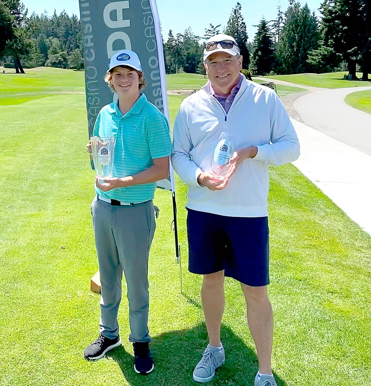 Cedars at Dungeness Ben Sweet, left, and Jim McCausland receive their trophies for winning at the Clallam County Amateur Golf Tournament. Sweet, a Sequim High School golfer, won the trophy for the best three-day gross score of 224. McCausland, a member of the Cedars at Dungeness Men’s Club, won the overall net championship with a score of 204. Sweet and McCausland each won $375 cash purses. (Photo courtesy of Cedars at Dungeness Golf Course)