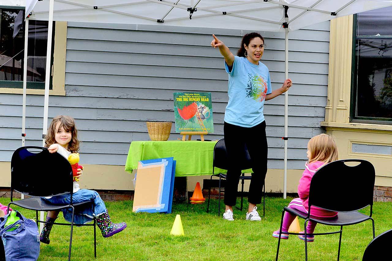 Rosaletta Curry, the Jefferson County Library’s early childhood program coordinator, begins story time by pointing out elements of the environment, such as trees. Ellie Long, 4, left, is among the listeners at story time outside the Port Townsend Library last Thursday. Story hours are offered free at libraries across the North Olympic Peninsula. For information, see NOLS.org and PTpubliclibrary.org. (Diane Urbani de la Paz/Peninsula Daily News)