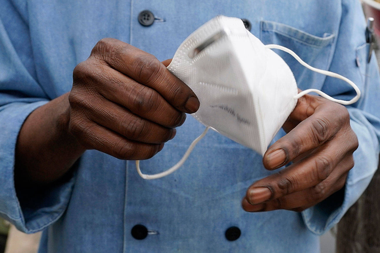 FILE - In this Friday, March 5, 2021 file photo, a restaurant worker holds his face mask in Biloxi, Miss. On Friday, March 12, 2021. The nation’s top health agency is expected to backpedal on its masking guidelines and recommend that even vaccinated people wear masks indoors in parts of the U.S. where the coronavirus is surging, according to a federal official who spoke on condition of anonymity because the official was not authorized to release the data. The Centers for Disease Control and Prevention is expected to make an announcement Tuesday, July 27, 2021. (AP Photo/Rogelio V. Solis)
