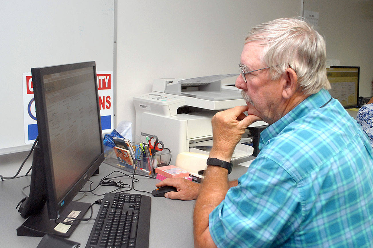 Clallam County election worker Daniel Cain of Sequim consults a database of signatures to verify ballots on Tuesday at the courthouse in Port Angeles. Results of the primary election were posted online Tuesday night, and they will be explored in depth in Thursday’s print edition. (Keith Thorpe/Peninsula Daily News)