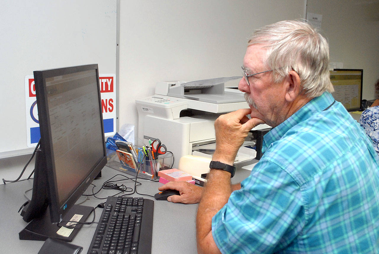 Clallam County election worker Daniel Cain of Sequim consults a database of signatures to verify ballots on Tuesday at the courthouse in Port Angeles. Results of the primary election were posted online Tuesday night, and they will be explored in depth in Thursday’s print edition. (Keith Thorpe/Peninsula Daily News)