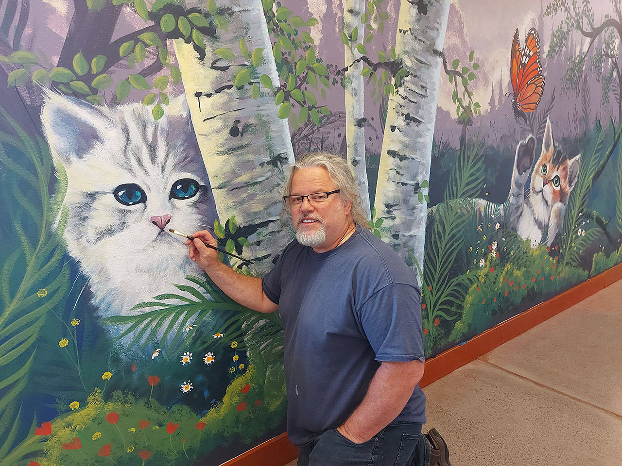 Port Angeles artist Dave Montague works on a mural at the Olympic Peninsula Humane Society’s McKay Kitty City near Sequim. (Photo courtesy of Olympic Peninsula Humane Society)