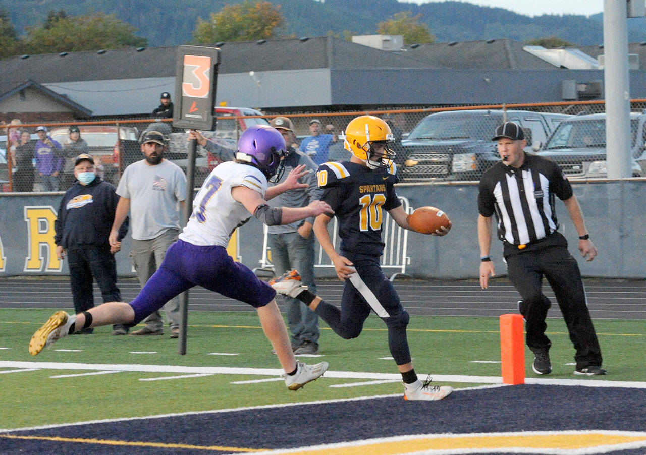 Lonnie Archibald/for Peninsula Daily News Forks quarterback Logan Olson outruns Sequim’s Mason King for a touchdown in the second quarter of the Spartans’ 56-28 season-opening win over the Wolves.