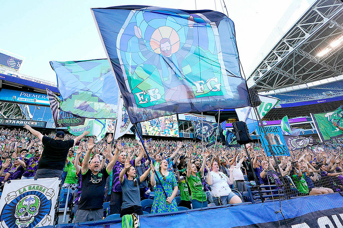 FILE - In this July 25, 2021, file photo, members of the Emerald City Supporters and other fans wave flags and cheer before an MLS soccer match between the Seattle Sounders and Sporting Kansas City in Seattle. Fans attending most pro sporting events in Seattle will soon be required to show proof they've been vaccinated against COVID-19 or that they've tested negative for the virus. The NFL's Seahawks, MLS's Sounders, NHL's Kraken and the University of Washington all announced updated policies Tuesday, Sept. 7, 2021, for fans attending games this season.  (AP Photo/Ted S. Warren, File)