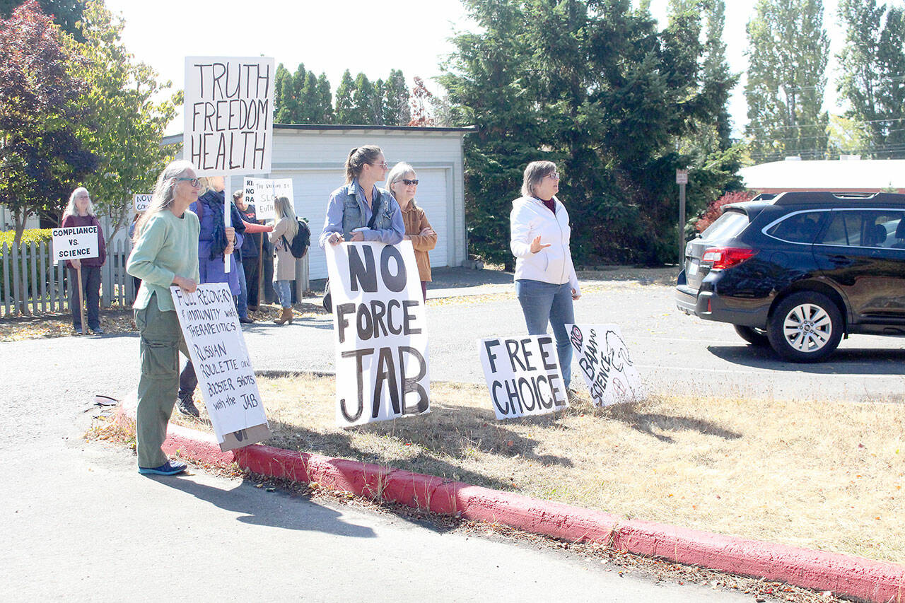 About 10 anti-vaccination protestors gather outside the Port Townsend High School campus Wednesday afternoon, holding a variety of signs such as "the vaccine is slow euthanasia" and equating getting the COVID-19 vaccine to playing a game of Russian roulette. (Zach Jablonski/Peninsula Daily News)