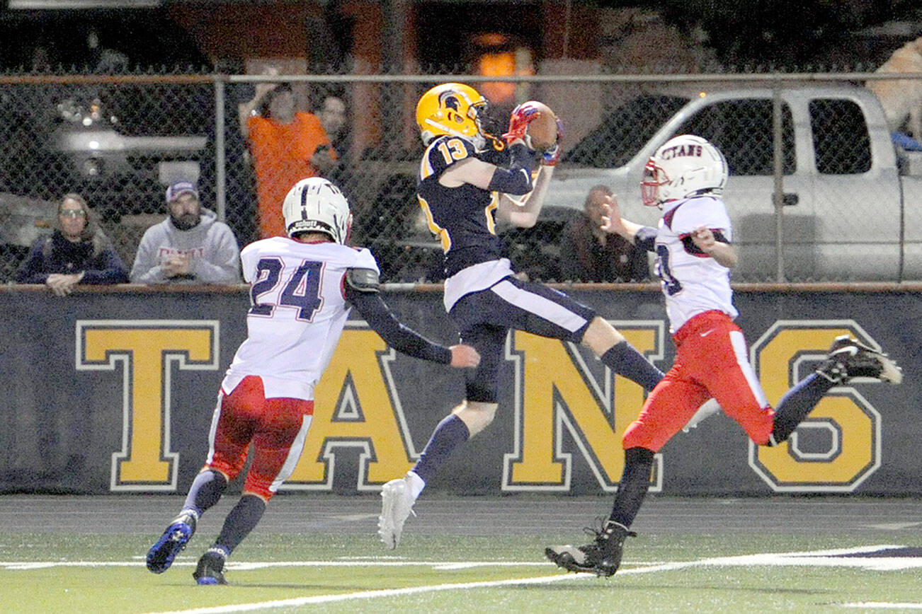 Spartan Ryan Rancourt (13) clutches a Logan Olson pass between two Titan defenders Friday night at Spartan Stadium where Forks defeated Pe Ell-Willapa Valley 22 to 21 in a thriller.  Photo by Lonnie Archibald.
