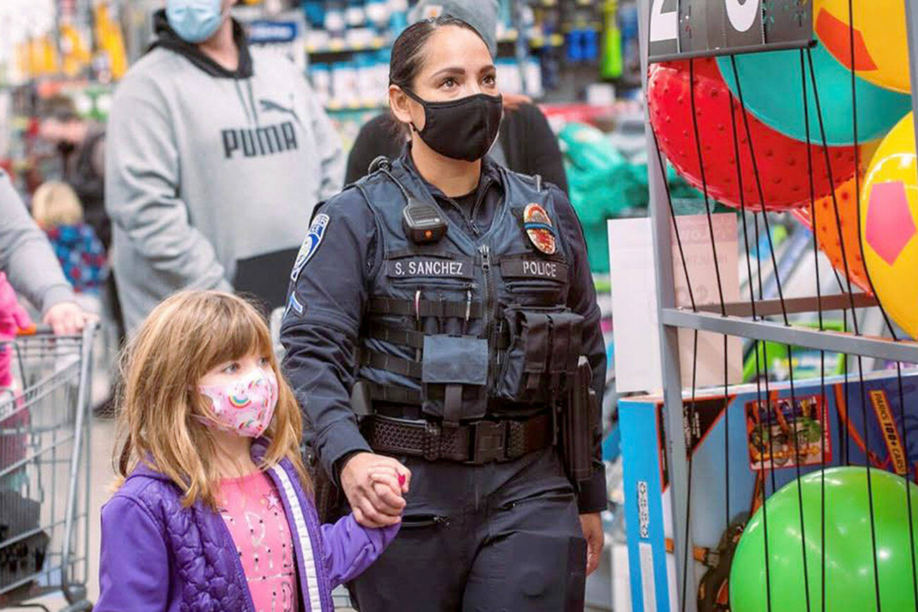 Port Angeles Police Officer Swift Sanchez with a child during a holiday shopping event. The police department is among several agencies in a partnership focused on resiliency throughout October. (Jesse Major Photography)