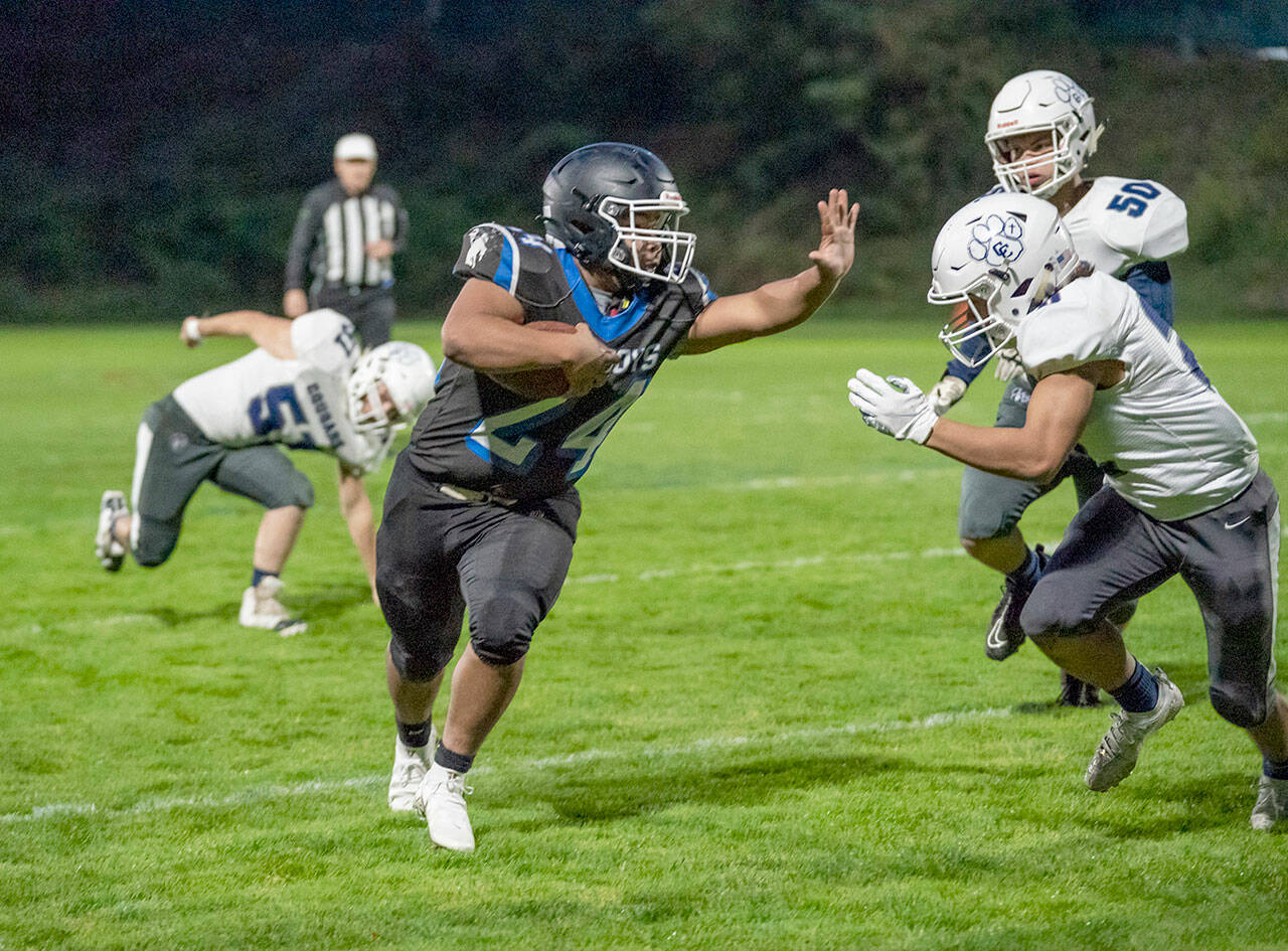 Steve Mullensky/for Peninsula Daily News East Jefferson Rival Anson Jones rushes around Cougars Brayden Metcalf (50) and Torin Carpenter (51) during a Friday night game played in Memorial Field in Port Townsend.