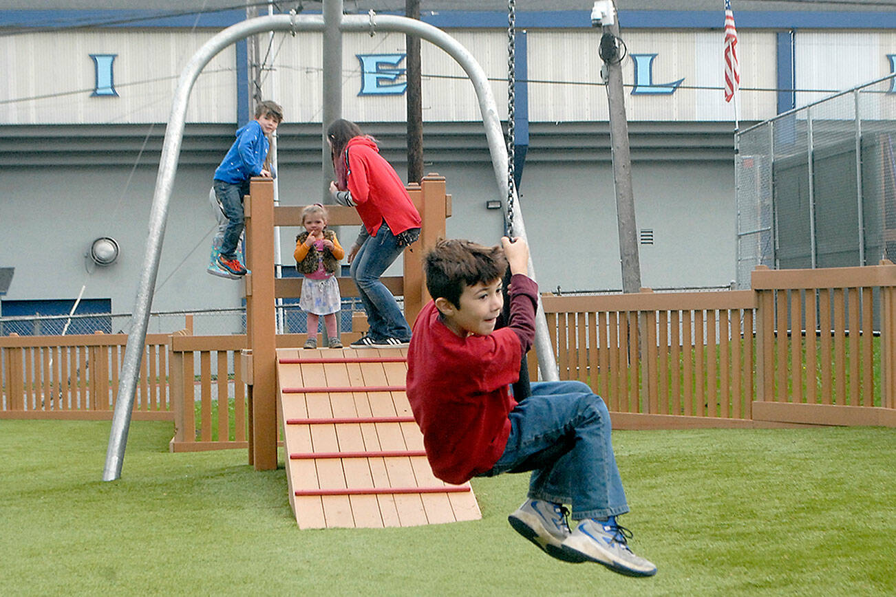 Ryan Belardi, 8, rides a zipline Wednesday at the Dream Playground at Erickson Playfield as siblings James Belardi, 6, and Hayleigh Belardi, 2, along with their mother, Rachel Belardi, all of Port Angeles, wait at the launch platform. (Keith Thorpe/Peninsula Daily News)