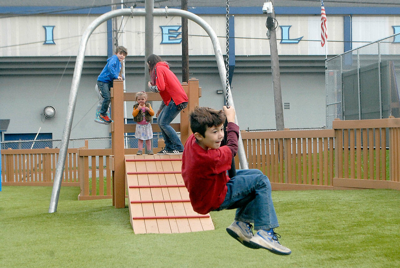Ryan Belardi, 8, rides a zipline Wednesday at the Dream Playground at Erickson Playfield as siblings James Belardi, 6, and Hayleigh Belardi, 2, along with their mother, Rachel Belardi, all of Port Angeles, wait at the launch platform. (Keith Thorpe/Peninsula Daily News)
