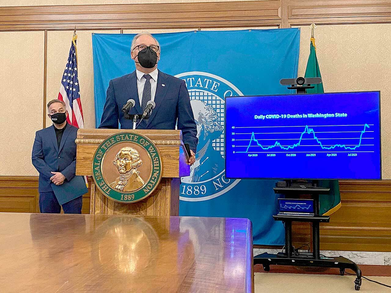 Gov. Jay Inslee, front, talks to reporters in Olympia earlier this month as Secretary of Health Umair Shah looks on. Inslee announced Thursday that 94 percent of state workers complied with a state mandate to either get the COVID-19 vaccine or be approved for an exemption. (Rachel La Corte/The Associated Press)
