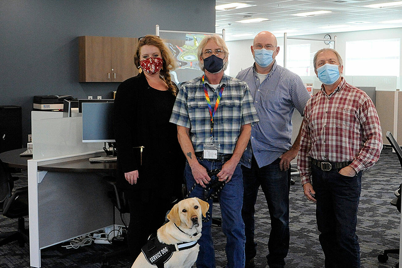 Some of the staff at WorkSource Clallam County stand in the resource lab where locals will soon be able to work on resumes, send emails and more as they seek new work. Pictured staff, include, from left, Claire Weaver, trade act, WIOA adult and dislocated worker for Clallam, Jefferson and Kitsap counties; Jon Ferguson, veterans employment specialist, with Professor the dog;  John Krouse, strategies for success instructor; and Brandino Gibson, supervisor. (Matthew Nash/Olympic Peninsula News Group)
