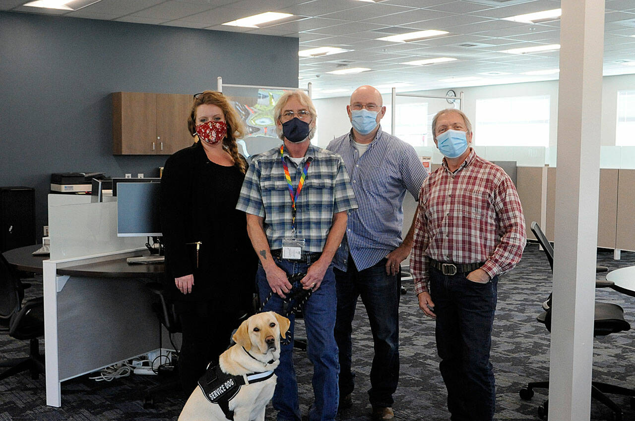 Some of the staff at WorkSource Clallam County stand in the resource lab where locals will soon be able to work on resumes, send emails and more as they seek new work. Pictured staff, include, from left, Claire Weaver, trade act, WIOA adult and dislocated worker for Clallam, Jefferson and Kitsap counties; Jon Ferguson, veterans employment specialist, with Professor the dog; John Krouse, strategies for success instructor; and Brandino Gibson, supervisor. (Matthew Nash/Olympic Peninsula News Group)