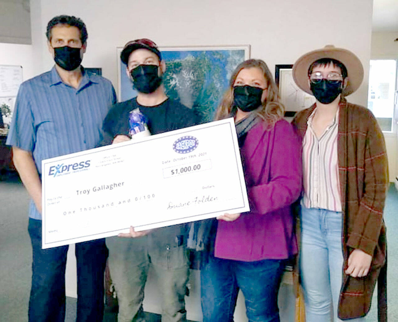 Troy Gallagher of Port Angeles, second from left, accepts a $1,000 jackpot from Express Employment Professionals employees Duane Folden, left, Shelley Mills and Kendra Lucke. Gallagher is one of 24 jackpot winners from across the country. The firm has 830 offices and more than 500,000 employees nationwide.