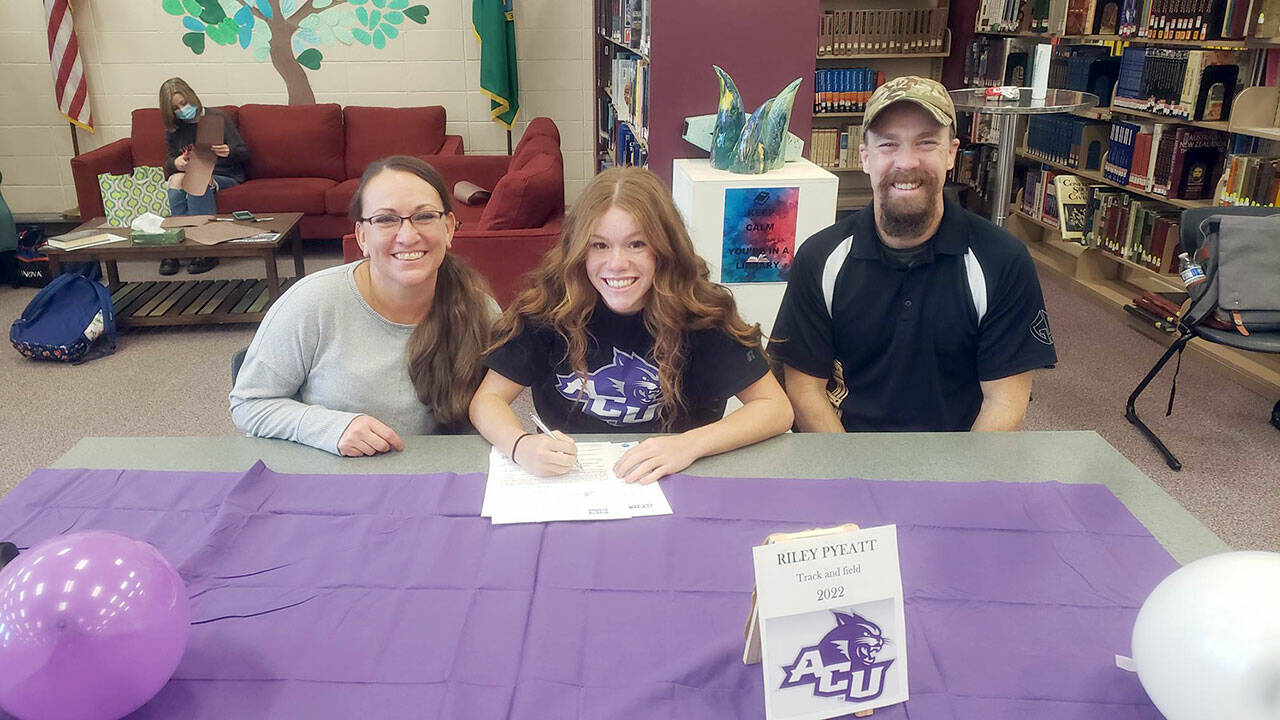 Sequim School District Sequim senior Riley Pyeatt, center, signs her Letter of Intent to run track at Abilene Christian University in Abilene, Texas. The Wildcats are a member of the NCAA Division I Western Athletic Conference. Pyeatt recently finished her senior cross country season with a fifth-place at the Class 2A state meet in Pasco. She is joined by mom Tracie and dad Doug Pyeatt.