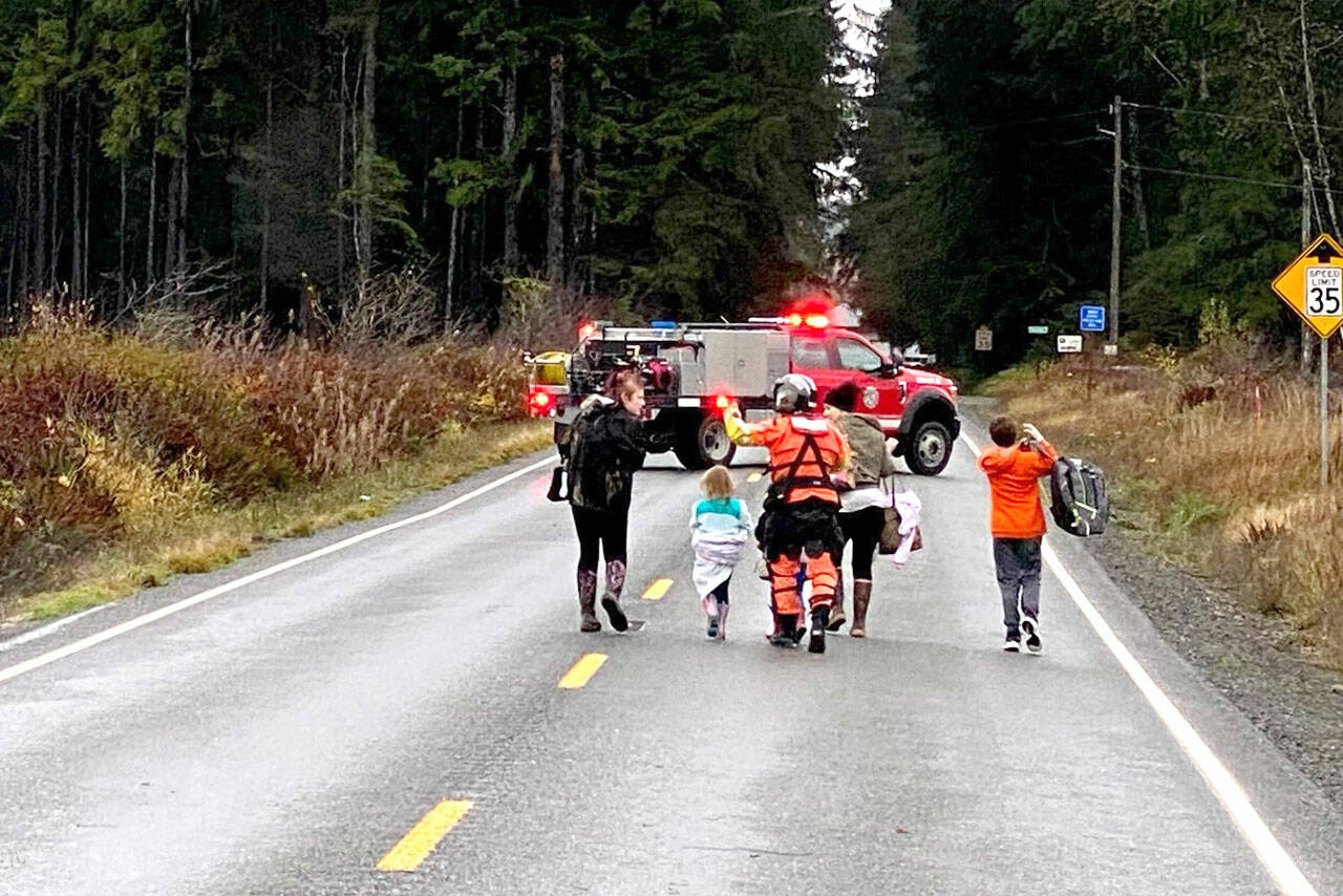 A Coast Guard rescue swimmer escorts multiple people who were evacuated from their residences during a flood near Forks, WA, Monday, Nov. 15. The crew evacuated a total of 10 people, including several children, after receiving a request for assistance from Clallam County emergency responders. (U.S. Coast Guard photo by Sector Columbia River)