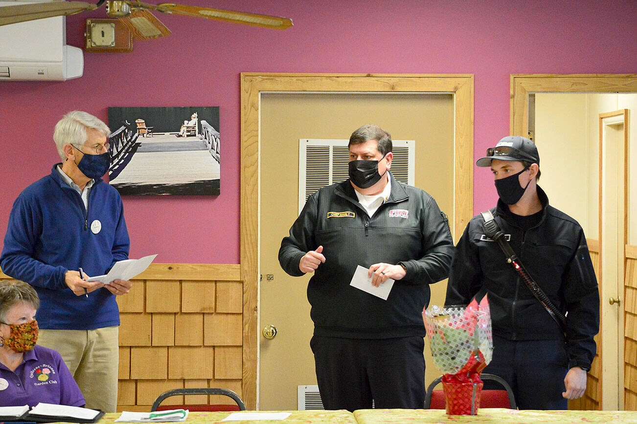 Bob Bindschadler of the Quilcene-Brinnon Garden Club, standing at left, and club president Ruth Dunham, seated, presented a $500 check to Brinnon Fire & Rescue chief Tim Manly, second from right, and Quilcene Fire & Rescue Lt. Nick Singleton last Thursday. Manly will use the funding to buy Guardian Angel LED safety lights for rural first responders to wear. Diane Urbani de la Paz/Peninsula Daily News