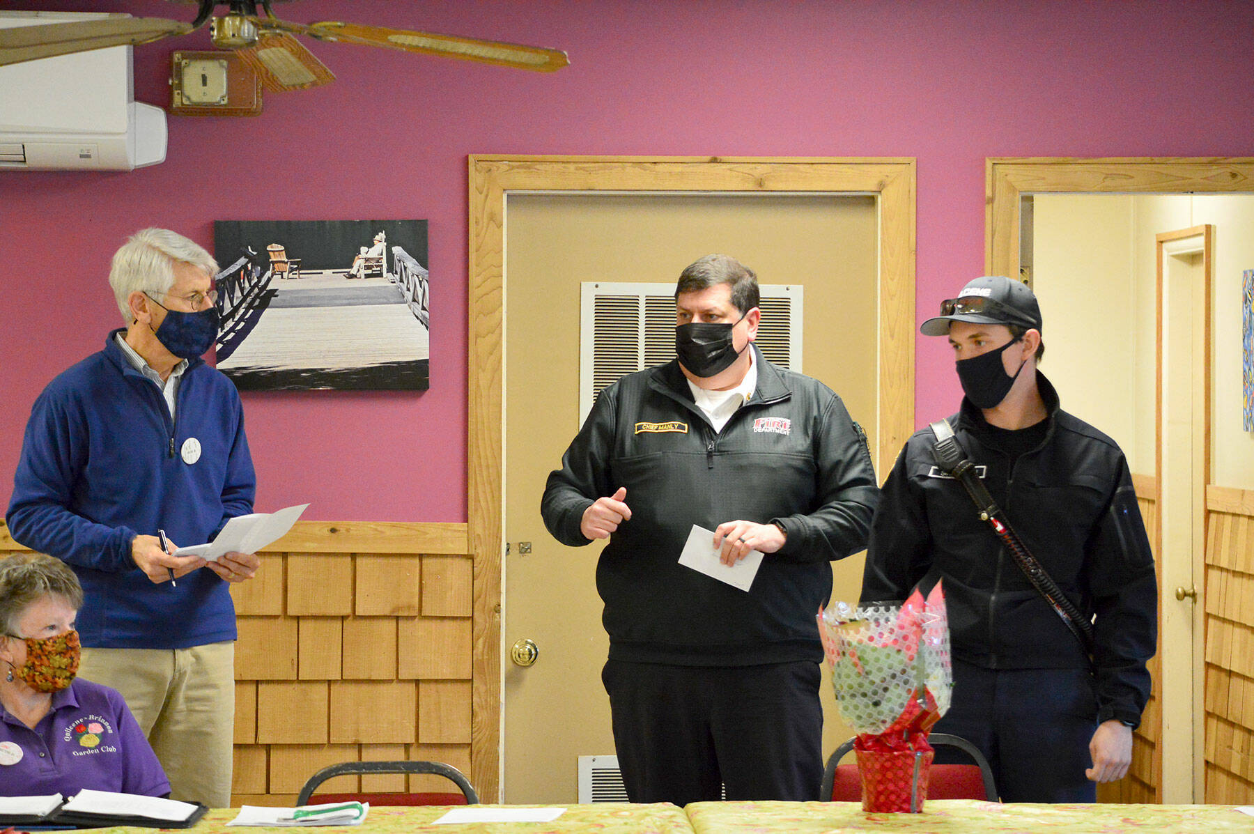 Bob Bindschadler of the Quilcene-Brinnon Garden Club, standing at left, and club president Ruth Dunham, seated, presented a $500 check to Brinnon Fire & Rescue chief Tim Manly, second from right, and Quilcene Fire & Rescue Lt. Nick Singleton last Thursday. Manly will use the funding to buy Guardian Angel LED safety lights for rural first responders to wear. (Diane Urbani de la Paz/Peninsula Daily News)