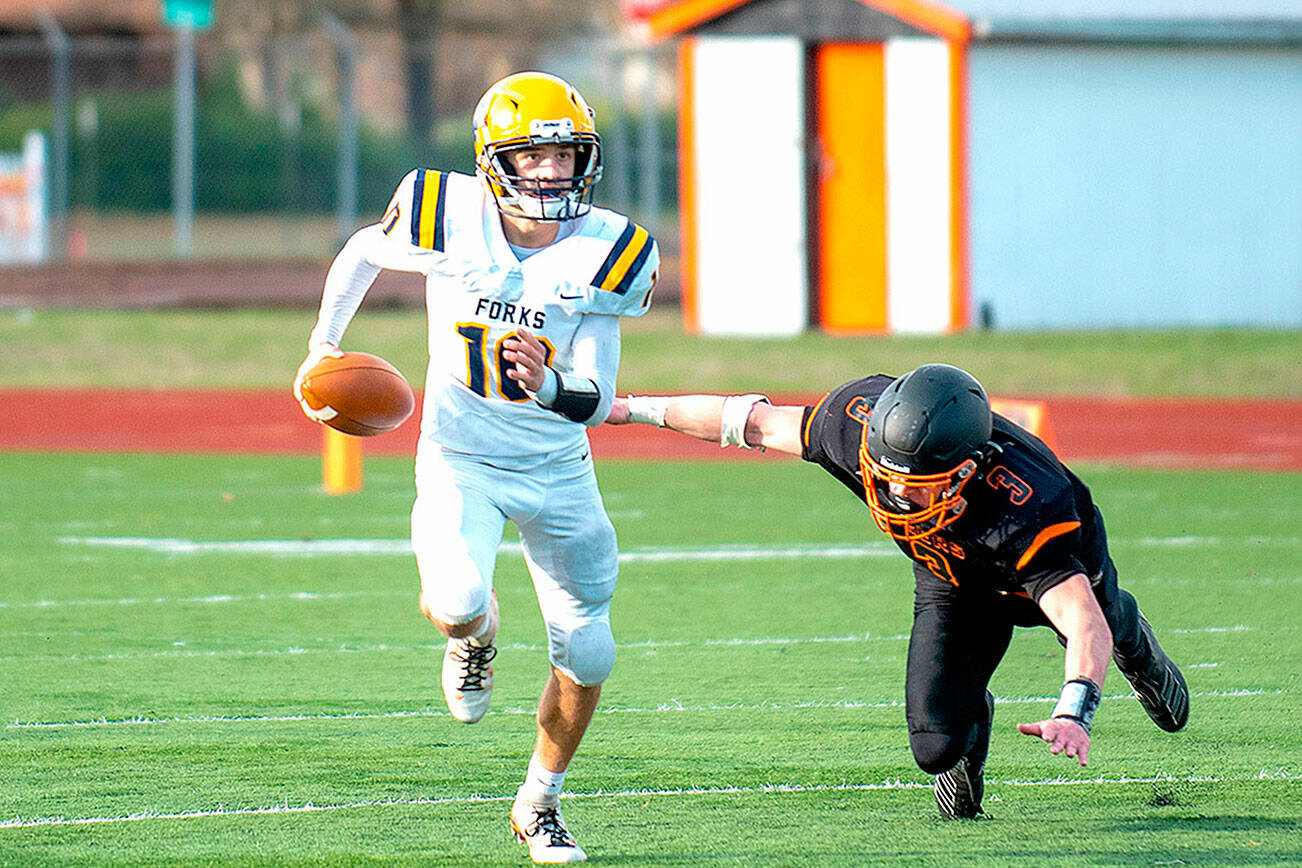 Eric Trent/The Chronicle
Forks quarterback Logan Olson avoids the rush against Napavine in the state 2B quarterfinal Saturday.