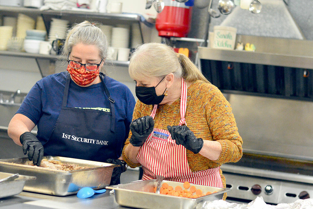 Volunteers Anita Schmucker and Judy Robinett are among the veteran crew members who served hundreds of takeout Thanksgiving meals at the Tri-Area Community Center on Thursday. (Diane Urbani de la Paz/Peninsula Daily News)