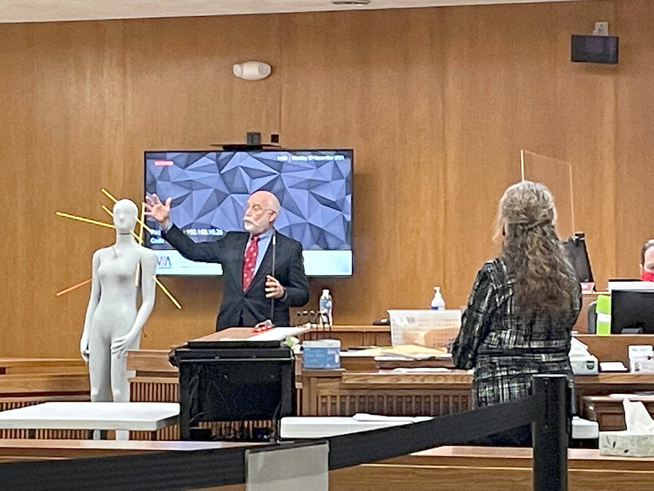 Dr. Eric Kiesel, the medical examiner who performed autopsies on the bodies of Tiffany May and Darrell and Jordan Iverson in January 2019, uses a manikin to show the trajectory of bullets during Dennis Mavin Bauer’s triple murder trial in Clallam County Superior Court. Michele Devlin, county chief criminal deputy prosecuting attorney, looks on. (Rob Ollikainen/ for Peninsula Daily News)