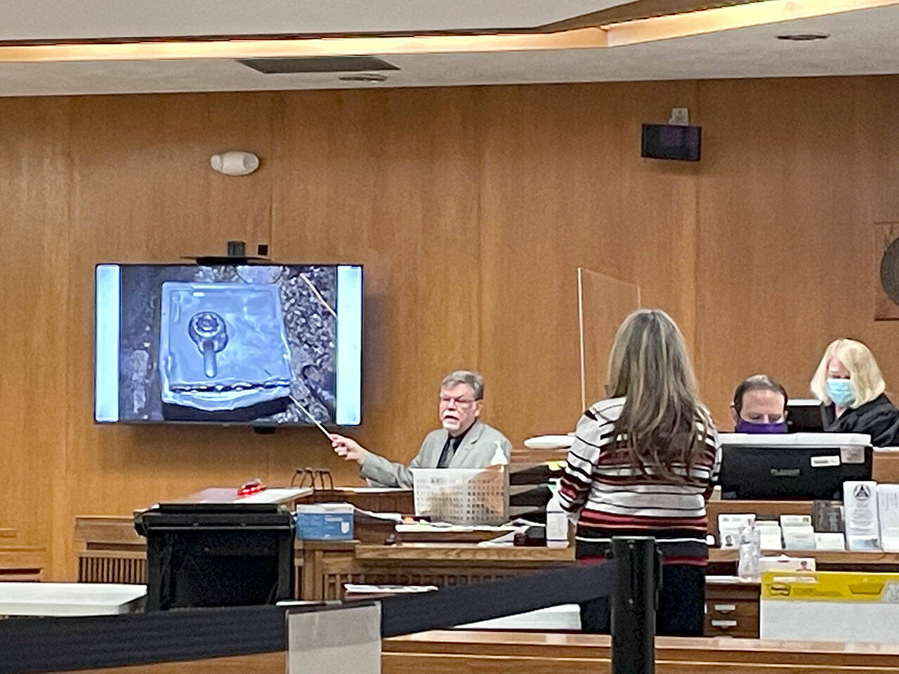 State Patrol forensic scientist Johan Schoeman displays a photograph Wednesday of a safe that was found after a triple murder in December 2018. (Rob Ollikainen/For the Peninsula Daily News)