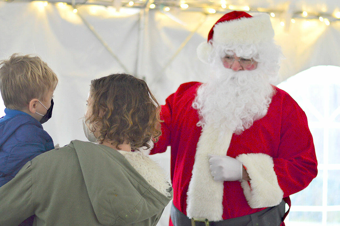 Dashiell Lemay, 4, supported by mom Amy Lemay of Port Townsend, fist-bumped with Santa Claus under the Tyler Street Plaza tent in Port Townsend on Saturday afternoon during the Port Townsend Main Street's seasonal activities that included a tree-lighting at dusk.   Diane Urbani de la Paz/Peninsula Daily News