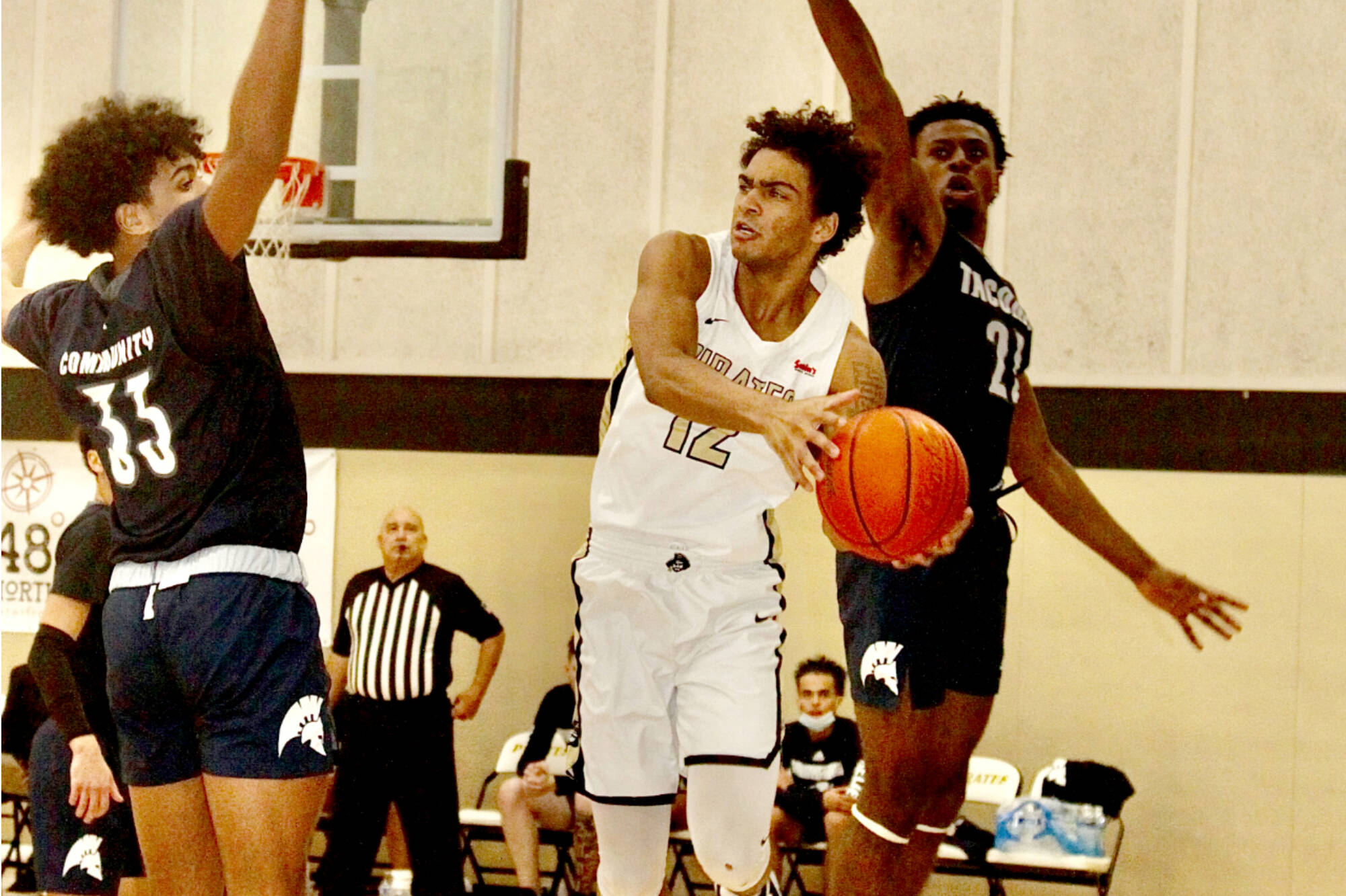 Peninsula College's Roosevelt Williams Jr. (12) looks to pass against Tacoma as he's guarded by Jared Franklin (33) and Daniel Mordi (21) on Sunday night in Port Angeles. Peninsula won the game 76-61.