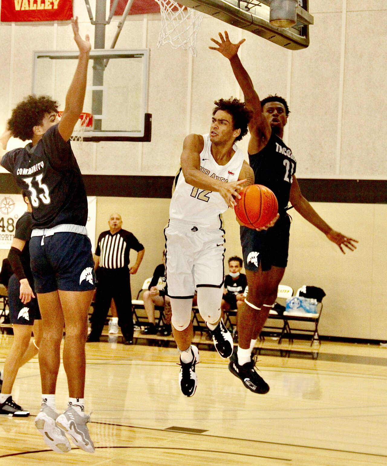 Peninsula Collegeās Roosevelt Williams Jr. (12) looks to pass against Tacoma as heās guarded by Jared Franklin (33) and Daniel Mordi (21) on Sunday night in Port Angeles. Peninsula won the game 76-62. (Dave Logan/for Peninsula Daily News)