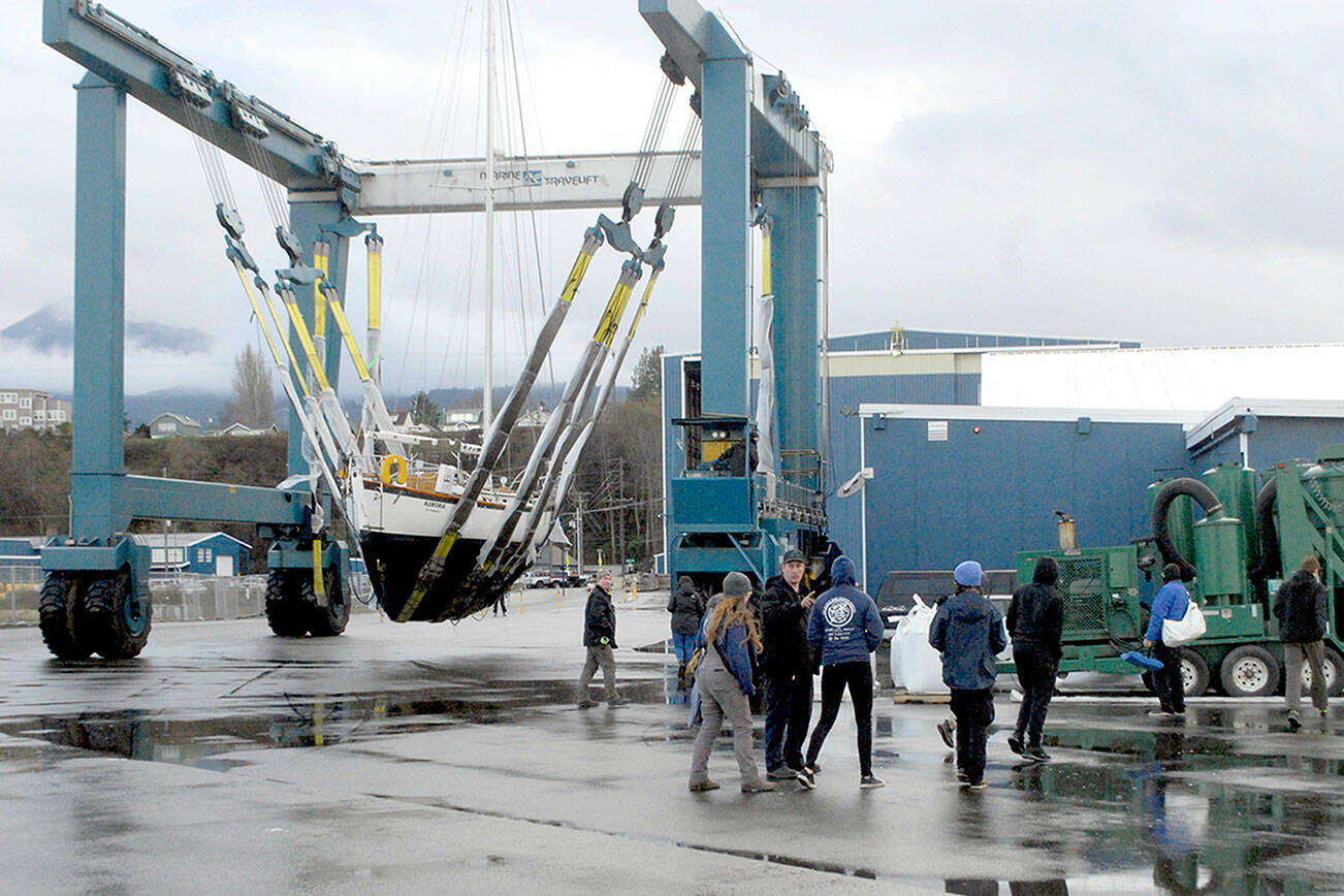 Members of the Marvin Shields Ship 1212 of the Sea Scouts watch as the sailboat Aurora is carried to the Platypus Marine Inc. shipyard for bottomside maintenance and inspection on Wednesday in Port Angeles. The boat, which was donated to the Seas Scouts by Arvo and Christiane Johnson, was hauled out by Platypus, which is donating much of the work, a total of about $5,000, the company said. Sea Scouts is a co-educational branch of the Boy Scouts of America that promotes boating skills and water safety for youths ages 14 to 20. (Keith Thorpe/Peninsula Daily News)