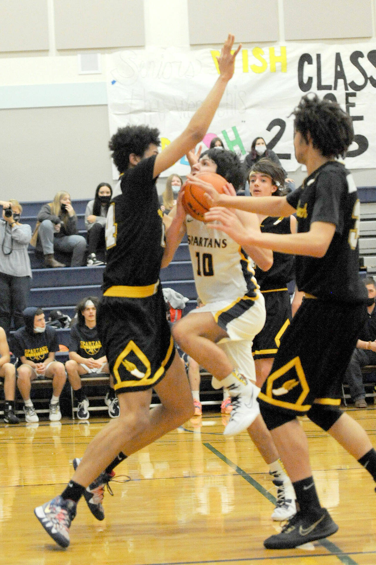 Forks’ Dylan Micheau drives the lane against North Beach’s 6-foot-7 Tre’ Vaughn Greene during the Spartans’ home opener Wednesday. (Lonnie Archibald/for Peninsula Daily News)