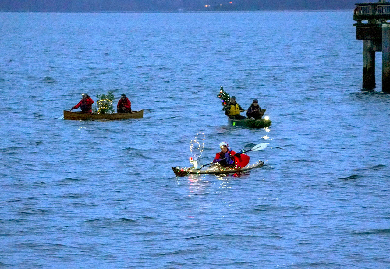 The three entrants in the non-motorized class of the holiday boat parade pass by the waterfront at Adams Street in downtown Port Townsend on Friday. (Steve Mullensky/for Peninsula Daily News)