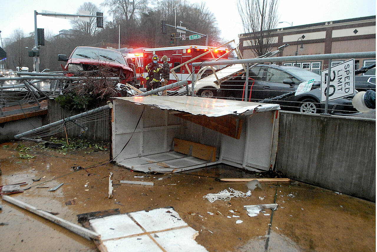 Emergency workers investigate after a westbound pickup truck lost control, struck a parked trailer on East Front Street and veered into a railing during Saturday’s farmers market at The Gateway transit center pavilion in downtown Port Angeles. Cpl. Erik Smith of Port Angeles police said the male driver apparently had a medical issue at the time of the wreck, but he and a juvenile passenger were uninjured. No market vendors were set up at the site of the incident, and no one at the market was injured. A parked car, a street sign and a light pole were also damaged. (Keith Thorpe/Peninsula Daily News)