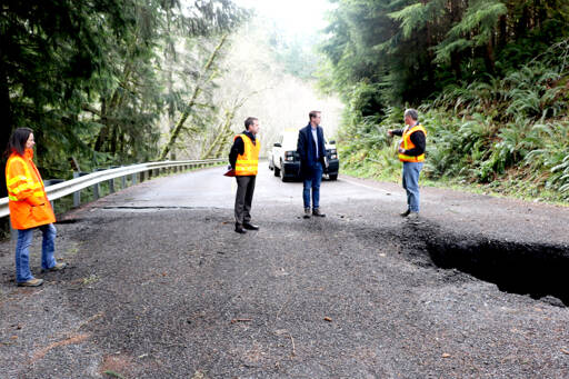 U.S. Rep. Derek Kilmer stands with workers from the state Department of Transportation who assess the damage of a landslide at Highway 112 near milepost 32. (Ken Park/Peninsula Daily News)
