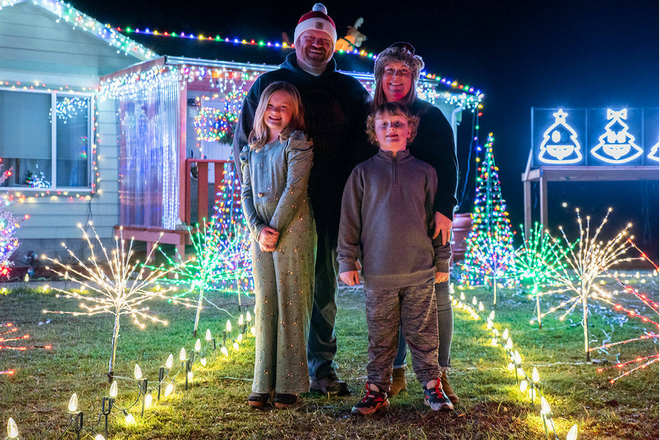 Emily Matthiessen / Olympic Peninsula News Group
The Bixby family, Emma, Corey, Tennille and Colin, stand in their yard, which they decorated with Christmas lights that are programmed to change with music.