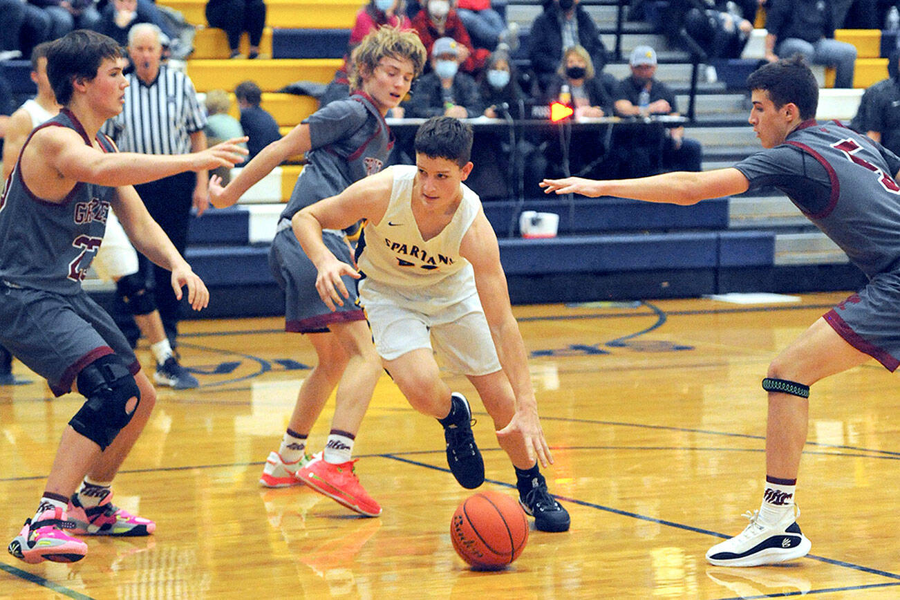 Spartan freshman Brody Lausche drives the key against Hoquiam's Justice Stankavich, (23), Zander Jump (10), and Owen NcNeill (5).  Forks defeated Hoquiam 54 to 39.  Photo by Lonnie Archibald.