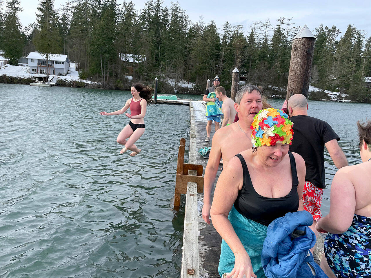 Theresa Britschg of Seattle and Chuck Sparks of Marrowstone Island walk back to the Nordland General Store after jumping into the chilly waters of Mystery Bay off the dock outside the store on Saturday. Behind them, Anna Watt of Marrowstone Island is captured in mid-jump. (photo by Will O’Donnell)