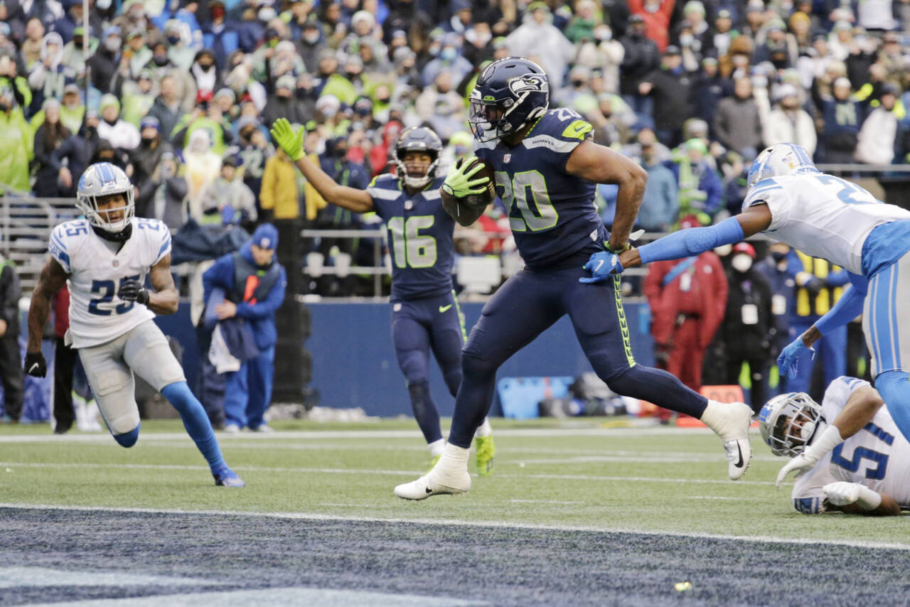 Seattle Seahawks running back Rashaad Penny (20) scores his second touchdown in the first half of an NFL football game against the Detroit Lions, Sunday, Jan. 2, 2022, in Seattle as Seahawks wide receiver Tyler Lockett (16) reacts in the background. (AP Photo/John Froschauer)