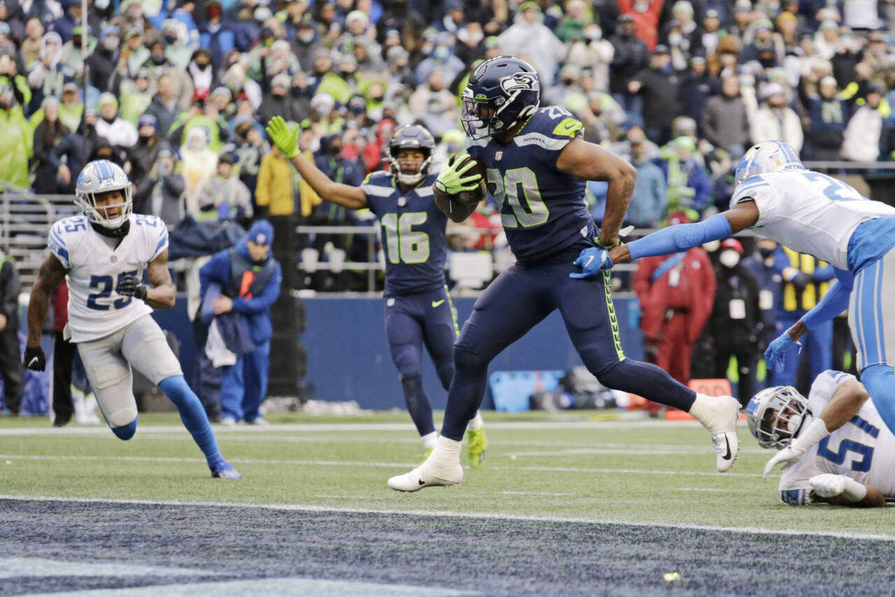 Seattle Seahawks running back Rashaad Penny (20) scores his second touchdown in the first half of an NFL football game against the Detroit Lions, Sunday, Jan. 2, 2022, in Seattle as Seahawks wide receiver Tyler Lockett (16) reacts in the background. (AP Photo/John Froschauer)