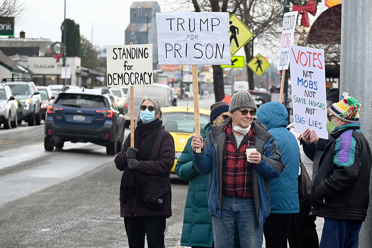 At least 125 people stand on the corners of Washington Street and Sequim Avenue on Thursday morning for a vigil on the one-year anniversary of the Jan. 6 insurrection at the U.S. Capitol. The vigil was hosted by Indivisible Sequim. Later in the day, the League of Women Voters of Jefferson County hosted in Port Townsend a candlelight vigil to remember the law enforcement officers killed or wounded on duty at the Capitol on Jan. 6 and to show support for voting rights. (Emily Matthiessen/Olympic Peninsula News Group)