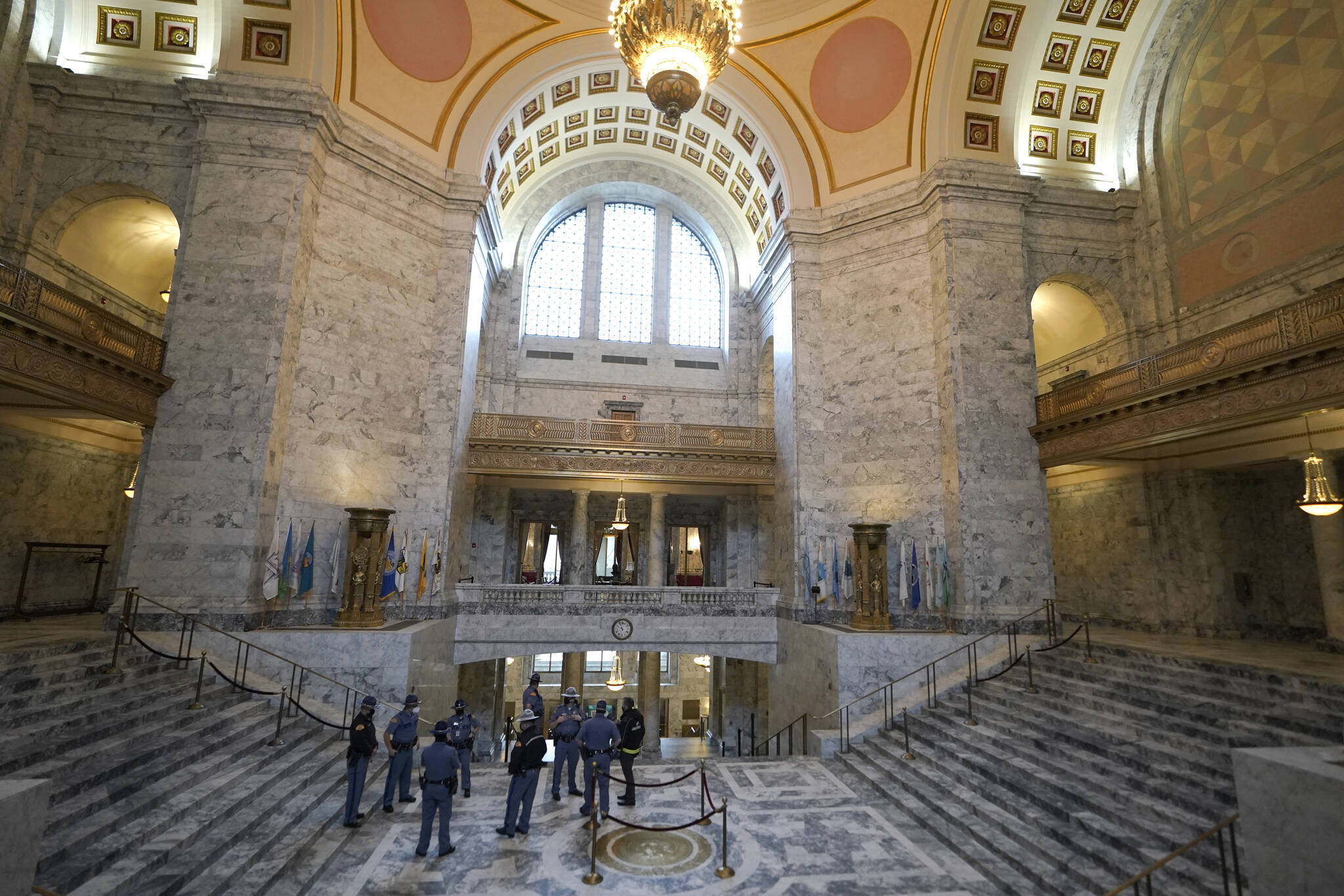 Washington State Patrol troopers stand near the state seal in the rotunda of the Legislative Building, Tuesday, Jan. 11, 2022, before Gov. Jay Inslee's scheduled State of the State address at the Capitol in Olympia, Wash. Due to cautions against COVID-19, Inslee will give the speech in the State Reception Room and it will be shown by streaming video to lawmakers meeting remotely. (AP Photo/Ted S. Warren)