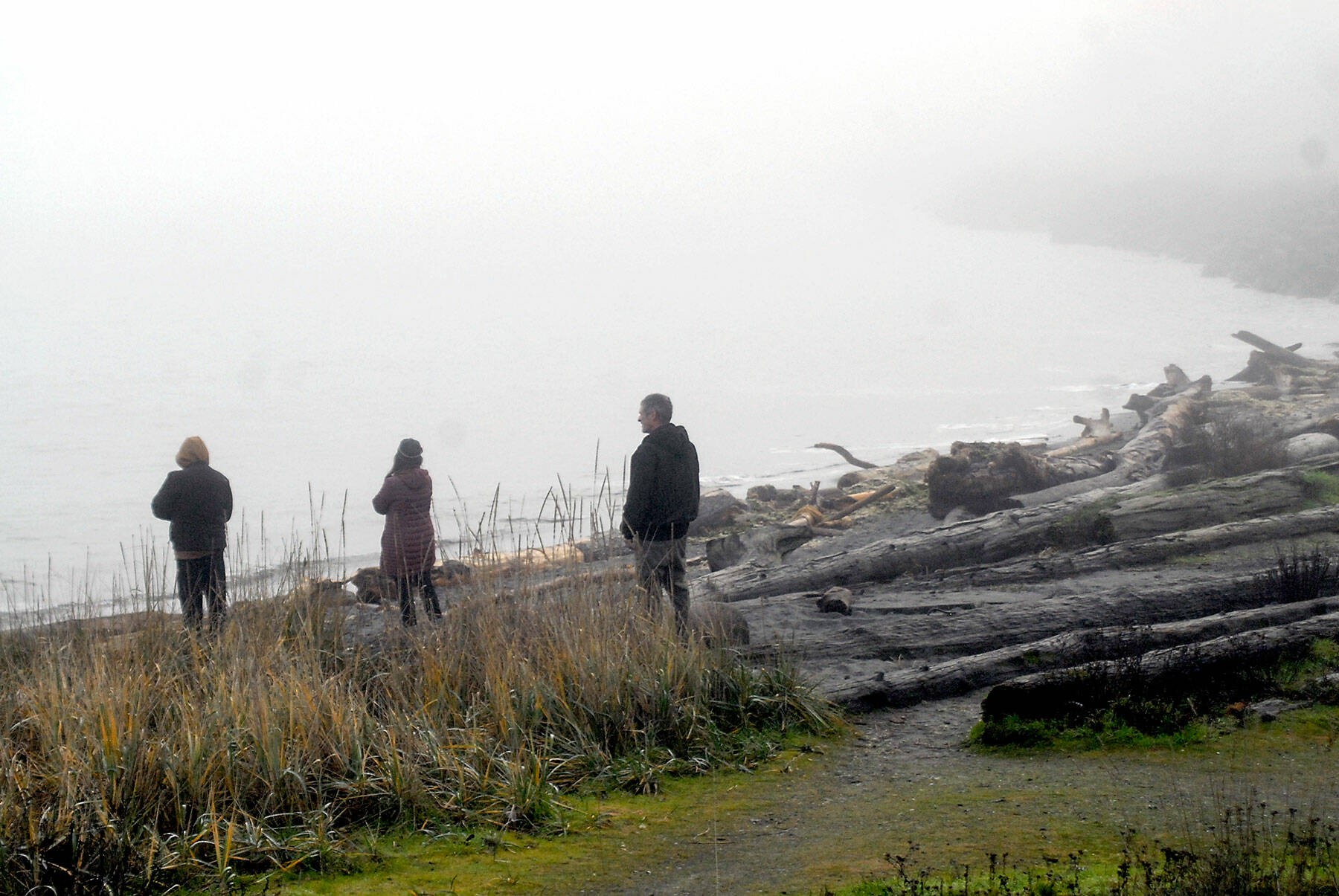 Onlookers stand on a fog -shrouded Hollywood Beach in Port Angeles after the most of the Pacific Coast was placed under a tsunami advisory on Saturday morning. (Keith Thorpe/Peninsula Daily News)