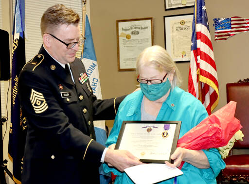 By Dave Logan/For Peninsula Daily News
First Sgt. Kent Keller of Sequim, left, presents to Linda Featheringill of Port Angeles the Purple Heart her brother was never able to receive in person as well as a United States of America War Office document. Her brother, Army Cpl. Marvin D. Actkinson, was declared missing in action in Korea on Dec. 2, 1950 and presumed dead in 1953. He was 18. His remains were returned in 2018 and will be buried in Colorado City, Texas, on Feb. 12. The Thursday ceremony was hosted by the Michael Trebert Chapter of the Daughters of the American Revolution at the Northwest Veterans Resource Center in Port Angeles. Featheringill was accompanied by her daughter Eilenah Moon. About 70 people attended the ceremony, which honored Actkinson 71 years after his death.