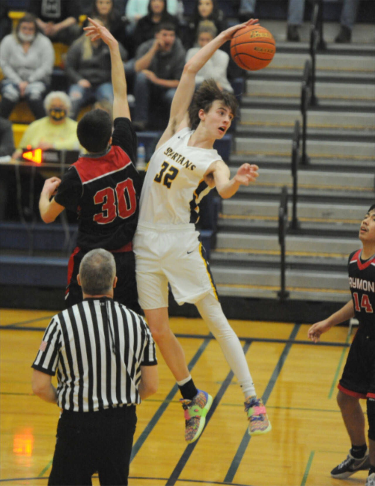 Forks’ Ryan Rancourt (32) out-jumps Raymond’s Morgan Anderson (30) to start the overtime portion of Saturday night’s league game played in Forks. The Spartans won 67-66. (Lonnie Archibald/for Peninsula Daily News)