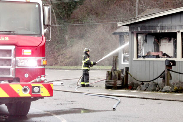 Ethan Grossell of the Port Angeles Fire Department cools hot spots left over from a fire at Castaways Restaurant Lounge early Monday morning. (Dave Logan/for Peninsula Daily News)