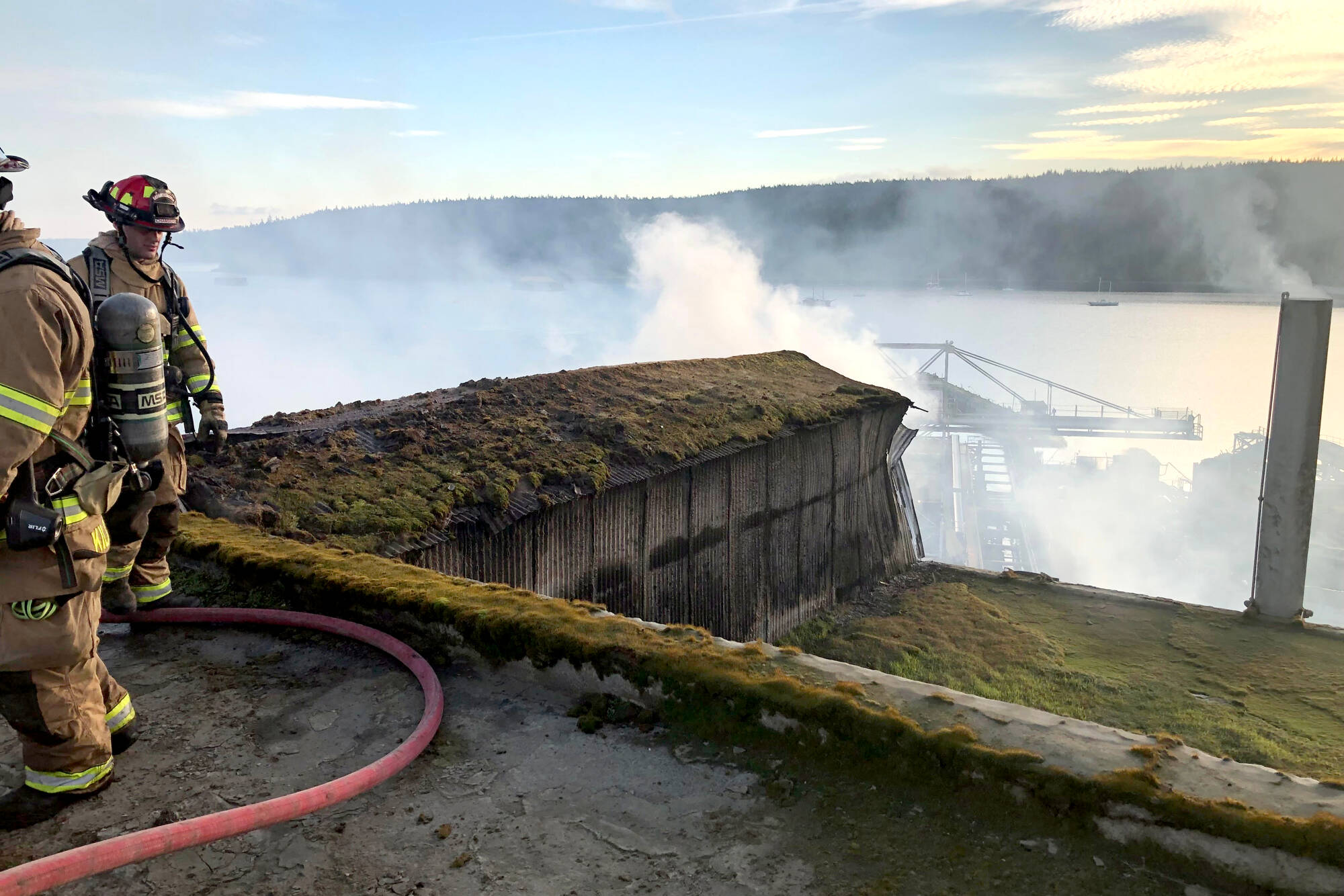 East Jefferson Fire Rescue Lt. Reece Chambers looks down from the roof of the Port Townsend Paper Corp. on Jan. 22, when a conveyor-belt fire caused some $500,000 in damage to the mill. (East Jefferson Fire Rescue)
