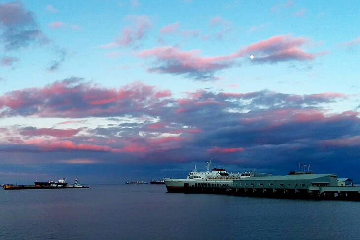 The Coho ferry arrives in Port Angeles from Victoria on Monday afternoon as the sun sets and the moon rises. The Canadian government announced the following day that, starting Feb. 28, travelers have the option of using a COVID-19 rapid antigen test rather than a PCR test, so long as it is administered by a health care professional. Also, “on arrival” in Canada, testing requirements will be eased for those who are fully vaccinated against the virus. (Pierre LaBossiere/Peninsula Daily News)