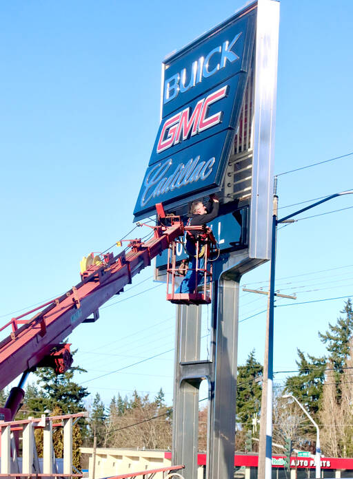 Dana Johnson of Esco Pacific Signs of Chehalis changes light bulbs and performs other maintenance on the Ruddell Auto Mall sign at the intersection of U.S. Highway 101 and Golf Course Road. (Dave Logan/for Peninsula Daily News)